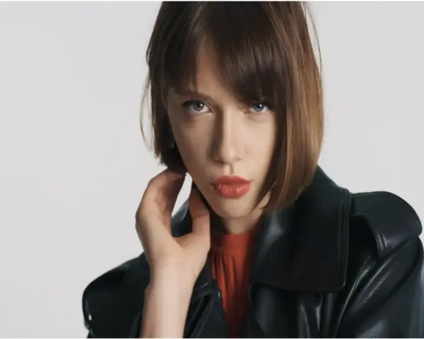Mujer con cortes bob modernos, mirada intensa y labios rojos, luciendo una chaqueta de cuero negra.