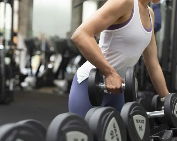 En person lyfter en hantel, tränar sina typ 1 muskelfibrer i gymmet.