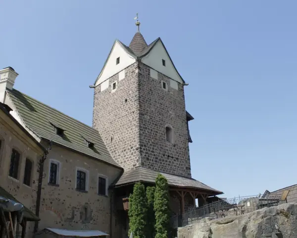 Kamienny zamek Loket z wieżą i budynkami mieszkalnymi pod błękitnym niebem.