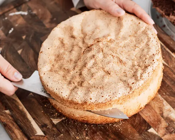 En person skär en fluffig sockerkaksbotten med en kniv. Perfekt för ditt nästa cake recept!