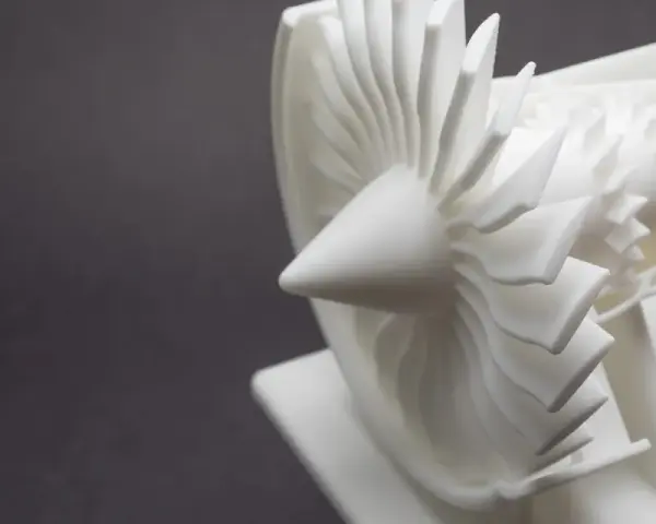 A detailed white model of a jet engine's turbine, showcasing intricate blades, likely created by a laser sintering machine.