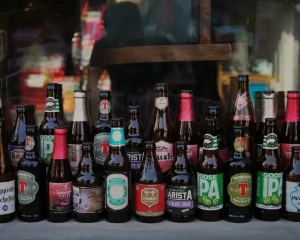 Rząd butelek z piwem kraftowym, w tym Trappistes Rochefort, Chimay, Goose Island i inne. Idealne na pytanie: jakie piwo kraftowe wybrać?