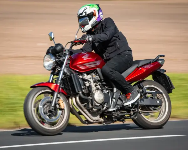 Motocyklista w kasku w stylu Jokera pędzi na czerwonym Honda CBF 600. Dane techniczne tego modelu są imponujące.