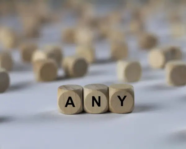 Holzwürfel mit den Buchstaben A, N, Y bilden das Wort "ANY". Sie liegen auf einem hellen Untergrund, umgeben von vielen weiteren unscharfen Würfeln.