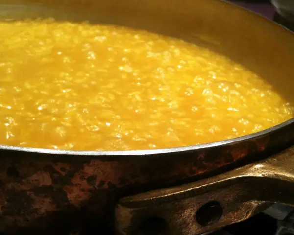 Un cremoso risotto alla milanese che sobbolle in una pentola di rame, pronto per essere gustato.