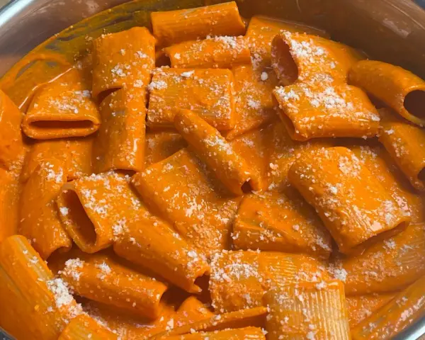 Rigatoni cremosa con un sugo rosso piccante, condita con parmigiano. Un piatto di pasta con nduja che fa venire l'acquolina in bocca.