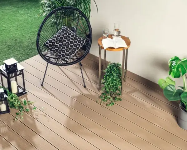 Drewno kompozytowe to świetny pomysł, czym wyłożyć balkon. Wygodne krzesło, stolik i rośliny tworzą przytulną przestrzeń.