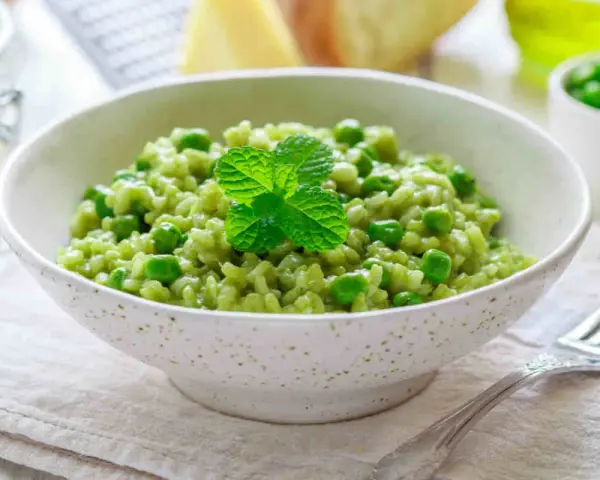 Un cremoso risotto con piselli, guarnito con menta fresca. Un piatto primaverile che celebra il gusto del riso e piselli.
