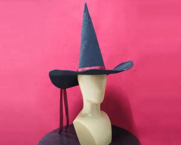 Un mannequin porte un patron chapeau pointu bleu foncé avec un ruban rouge. Deux rubans rouges pendent de chaque côté.