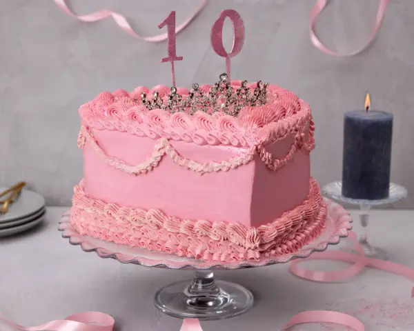 Prinzessin Torte ohne Fondant, dekoriert mit rosa Buttercreme-Rüschen und einer glitzernden Krone. Die Zahl 10 steht für den 10. Geburtstag.