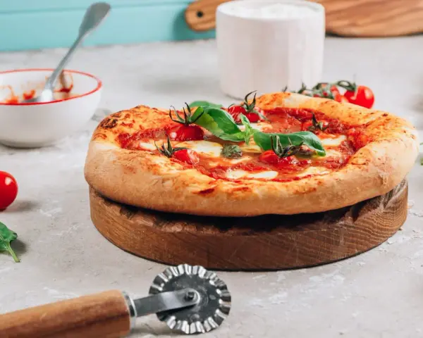 Pyszna pizza na drewnianej desce, gotowa do pokrojenia. Idealna na to, na czym piec pizze.