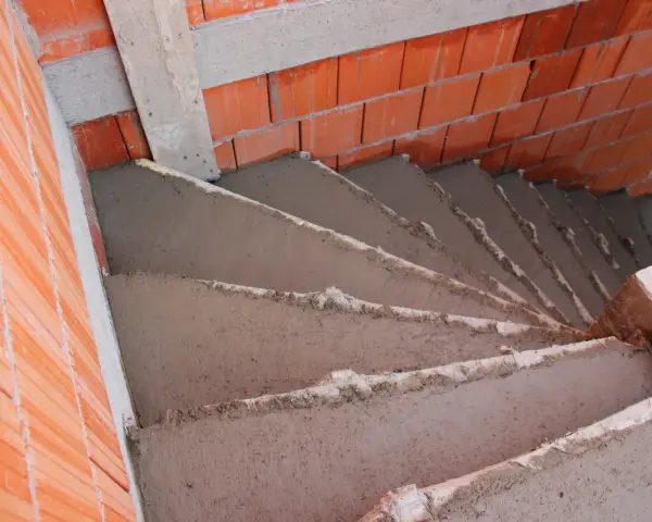 Escalier en béton brut, 5 marches en cours de construction, entouré de briques rouges. Estimation du prix escalier béton extérieur 5 marches.