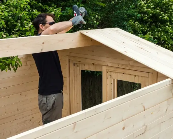 Hombre montando una caseta de madera. La madera clara y resistente es la mejor madera para exterior.