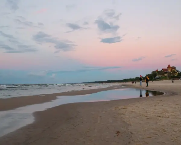 Zachód słońca nad morzem w kurorcie niedaleko Lęborka. Piękne, pastelowe niebo odbija się w wodzie na plaży.