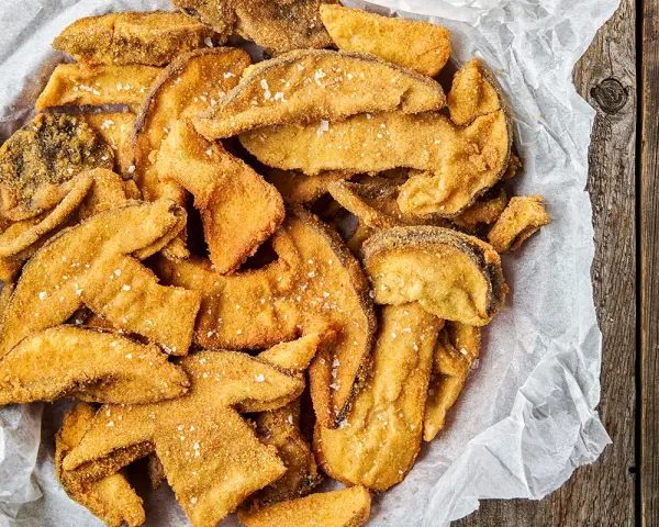 Un cesto pieno di croccanti funghi fritti, cosparsi di sale grosso, pronti per essere gustati.