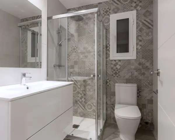 Salle de bain moderne avec douche vitrée, lavabo suspendu et carrelage graphique. Un projet pour agrandir salle de bain avec style.