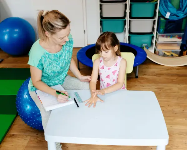 Terapeuta ocenia reakcje dziecka podczas badania sensorycznego, sprawdzając jego wrażliwość dotykową i propriocepcję.