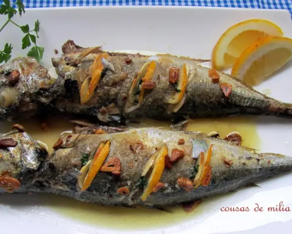 Dos jureles al horno, dorados y jugosos, con rodajas de limón y ajo. Un plato sencillo y delicioso.