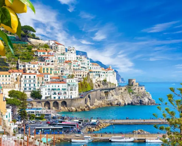 Costiera Amalfitana, un sogno di **Italia in moto** tra limoni e mare blu. Case bianche aggrappate alla roccia, un borgo pittoresco.