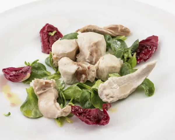 Delicato tonno di coniglio servito con insalata fresca e radicchio croccante, condito con olio d'oliva.