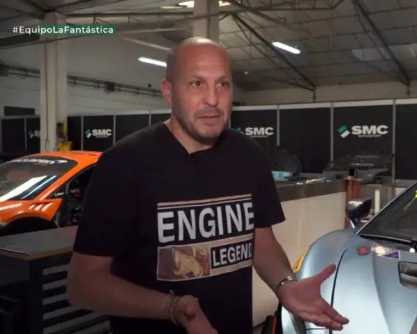 Fernando Navarrete, piloto, habla en un taller con autos de carrera.