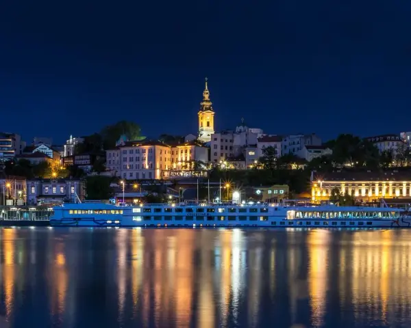 Nocny Belgrad z rzeką i statkiem wycieczkowym. Czy do Serbii potrzebny jest paszport? Sprawdź przed podróżą!