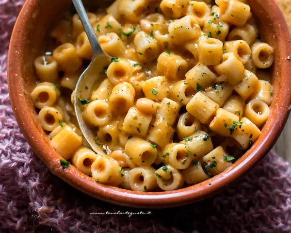 Un piatto fumante di pasta e fagioli, con ditalini e fagioli borlotti in un sugo cremoso, guarnito con prezzemolo tritato.