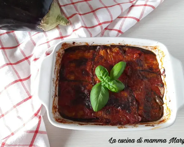 Parmigiana di melanzane non fritte, appena sfornata, guarnita con basilico fresco. La ricetta perfetta per un piatto leggero e gustoso.