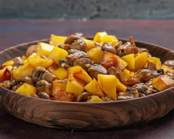 Un delicioso salteado de setas y patatas doradas en un cuenco de madera.