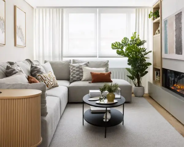 Sofá gris, mesa de centro negra, chimenea moderna y mueble de madera. Una sala acogedora, perfecta para una reforma sin obras.
