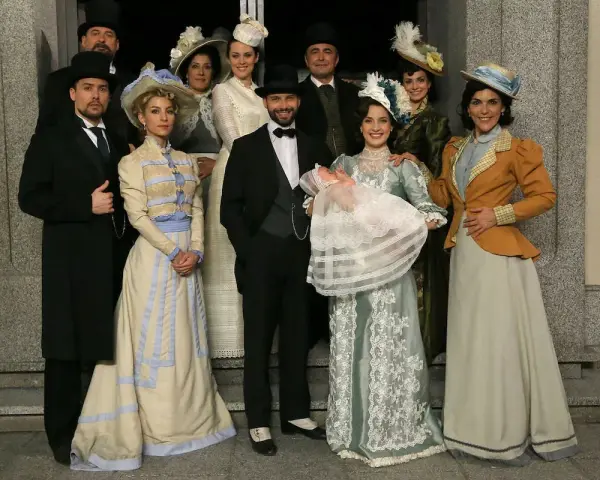 Un gruppo di persone in abiti d'epoca, con un neonato in braccio, anticipazioni una vita di famiglia e tradizione.
