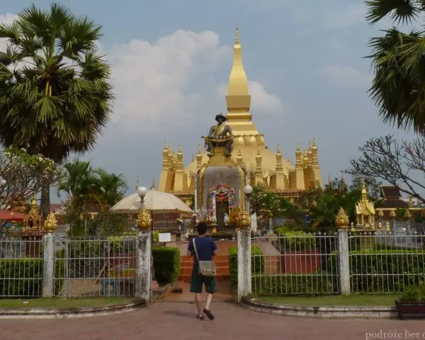 Złota stupa Pha That Luang, symbol stolicy w Wientianie, otoczona palmami i zielenią.