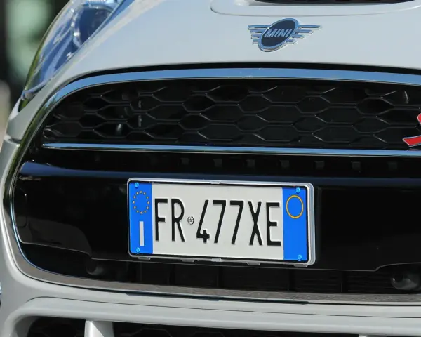 Targa di immatricolazione auto estera su una Mini Cooper S bianca.