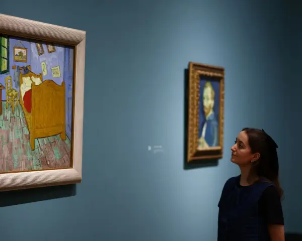 Deux femmes contemplent des tableaux. À gauche, la chambre de Van Gogh, une œuvre iconique dont le prix tableau peinture à l'huile fascine.