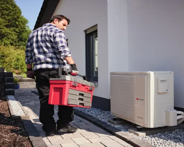 Technik z walizką narzędziową przy pompie ciepła. Może sprawdzać kody błędów urządzenia.