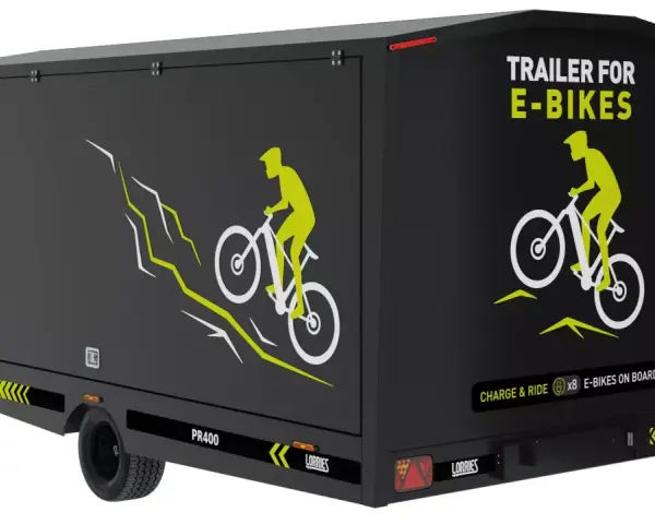 Czarna rowerowa przyczepa kempingowa z grafiką rowerzysty na górskim szlaku. Napis "TRAILER FOR E-BIKES" i "CHARGE & RIDE x8 E-BIKES ON BOARD".