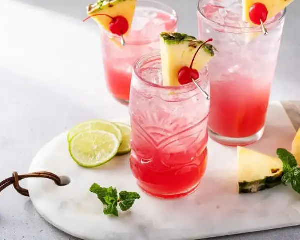 Orzeźwiający drink z ginem, ozdobiony ananasem i wiśnią, z dodatkiem limonki i mięty. Idealny na letnie popołudnie.