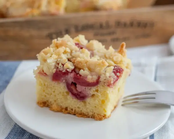 Ein Stück Kirsch-Streuselkuchen, perfekt für ein einfaches Crumble Rezept. Saftige Kirschen unter knusprigen Streuseln.