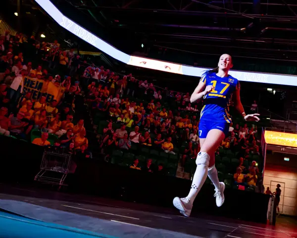 En spelare i Sveriges damlandslag i fotboll, nummer 17, springer ut på planen inför en jublande publik.