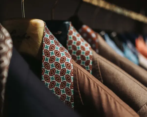 Un guardaroba elegante con giacche marroni e camicie dal tessuto dalle tinte diverse e vivaci, con fantasie geometriche.