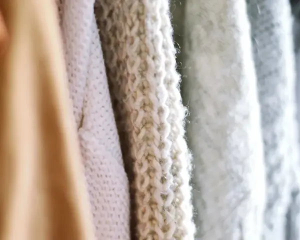 Nahaufnahme von Strickwaren in verschiedenen Pastelltönen. Die feine Struktur zeigt, dass Merinowolle fusselt, was den weichen Charakter unterstreicht.