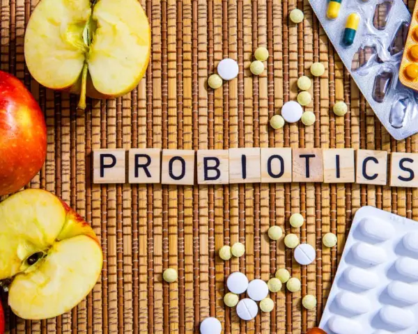Äpfel und Pillen umgeben das Wort "PROBIOTICS". Eine natürliche Methode, probiotika gegen akne zu finden.