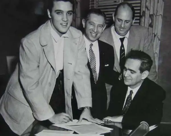 Elvis Presley unterschreibt Dokumente, ein wichtiger Schritt für seinen späteren Elvis Presley net worth.