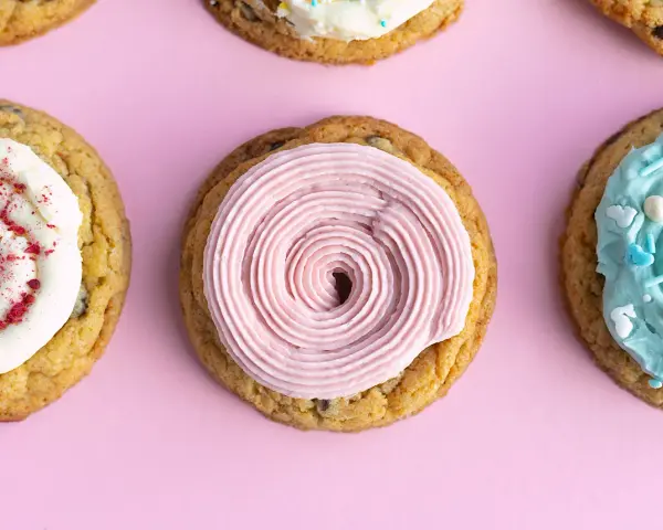 Galletas americanas decoradas con glaseado rosa, blanco con frambuesa y azul con chispas. ¡Una deliciosa receta para compartir!