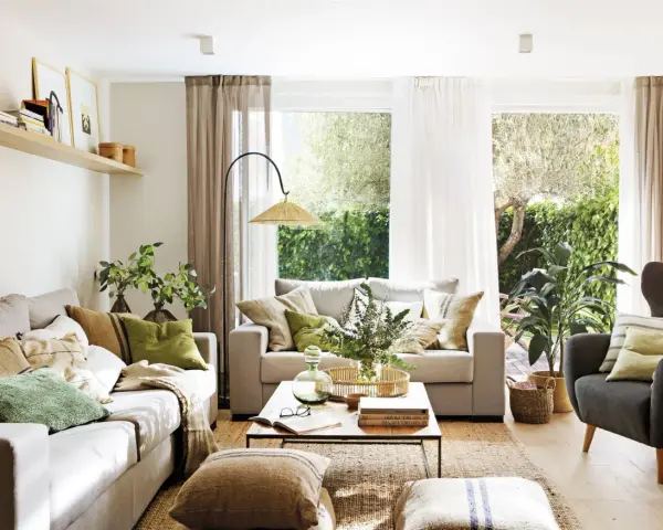 Salón con sofás, sillón, mesa de centro y alfombra de yute. La decoracion aesthetic se realza con cojines en tonos tierra y verdes, plantas y luz natural.