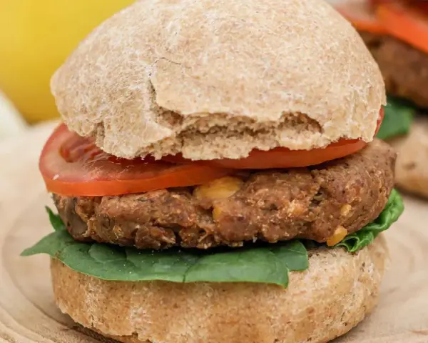 Hamburguesa de legumbres con pan integral, tomate y espinacas.