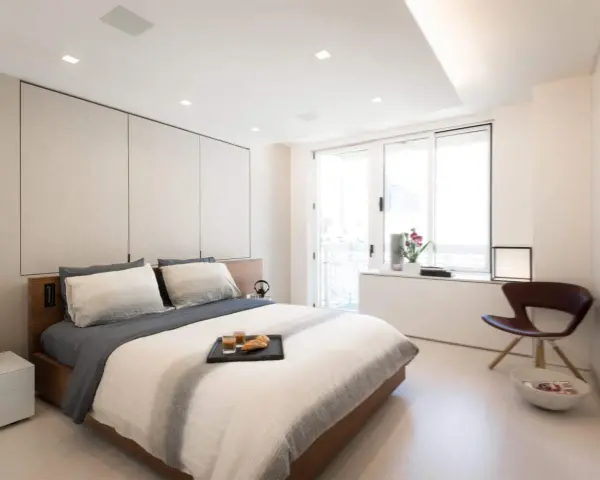 Camera da letto moderna con letto king-size, pannelli imbottiti e soffitto con faretti e strisce led controsoffitto che creano un'atmosfera rilassante.
