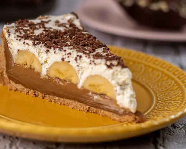 Kawałek banoffee pie z bananami, kremem i czekoladą na żółtym talerzu. Nie tarta cytrynowa, ale pyszny deser!