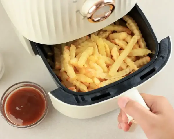 Air fryer co to? To urządzenie, które przygotuje chrupiące frytki bez nadmiaru tłuszczu. Obok sosy i majonez.