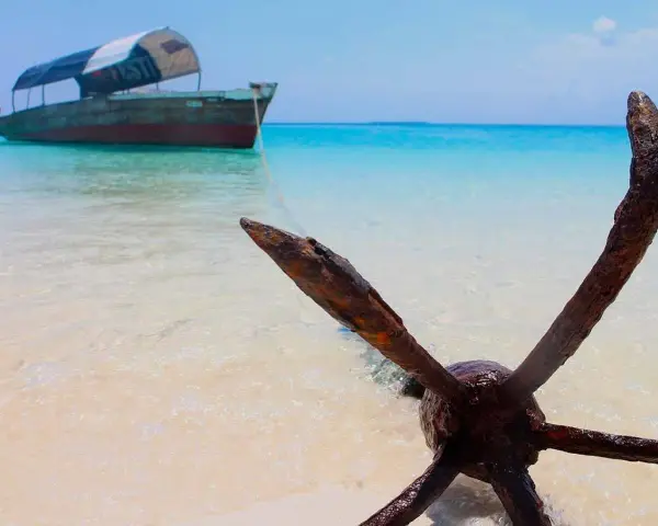 Kotwica na plaży, łódź na turkusowym morzu. Idealne miejsce na Zanzibar wycieczki fakultatywne.